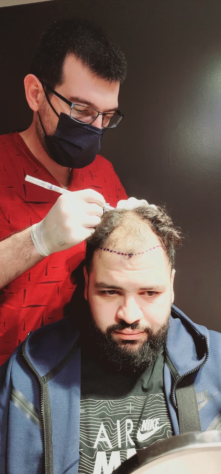 A clinician marking a patient's hairline with a surgical pen