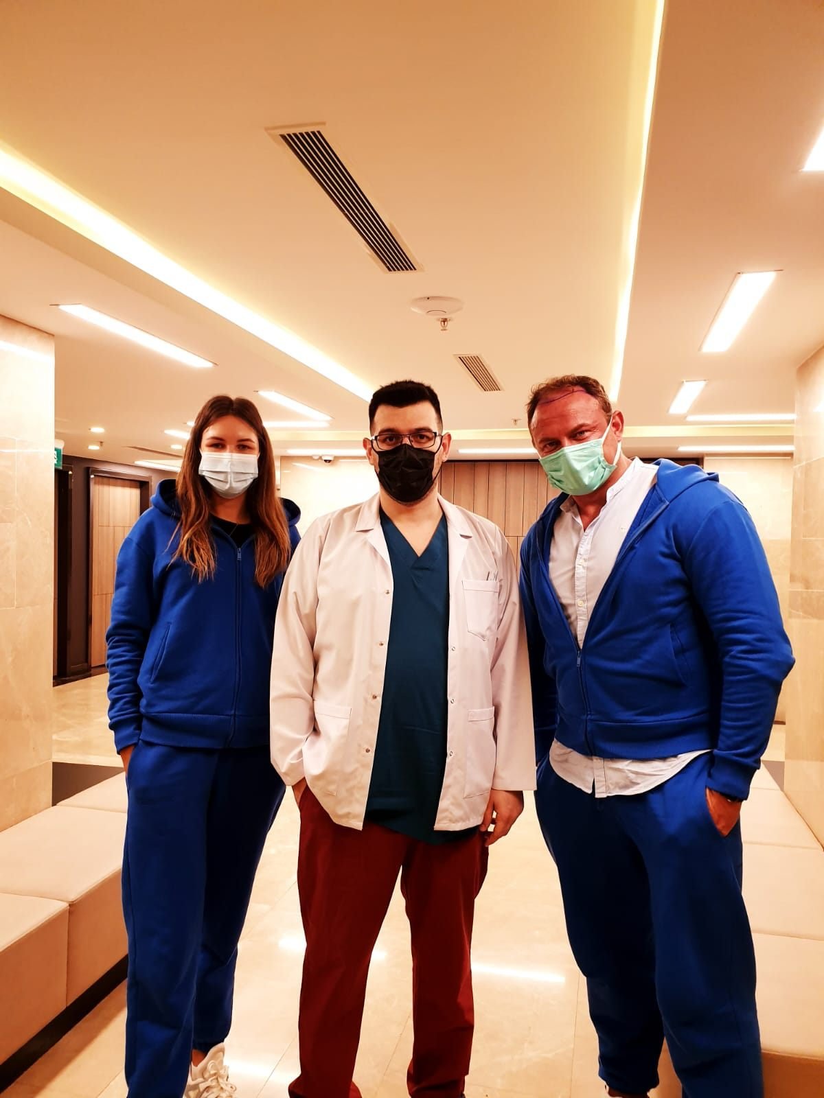 A patient and companion with the doctor in a hospital corridor